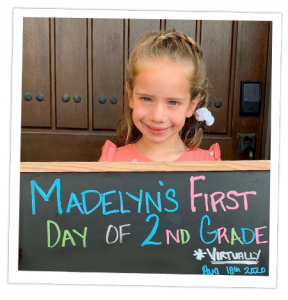 Transplant recipient, Madelyn, holding a chalkboard commemorating her first day of 2nd grade