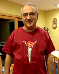 John wearing a red t-shirt with printed zipper opening to reveal a heart with bandage over words of Zipper Club