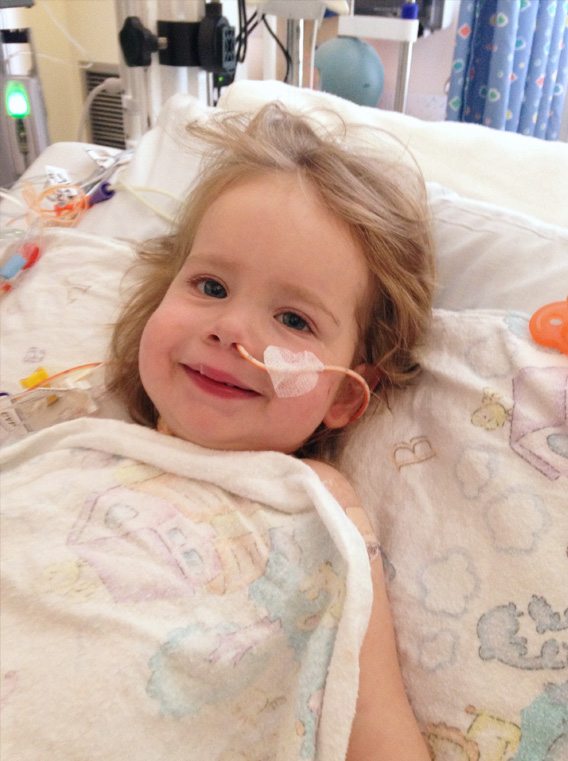 Heart recipient, Madelyn, smiling in hospital bed