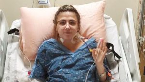 Samantha with hand up, waving, from hospital bed